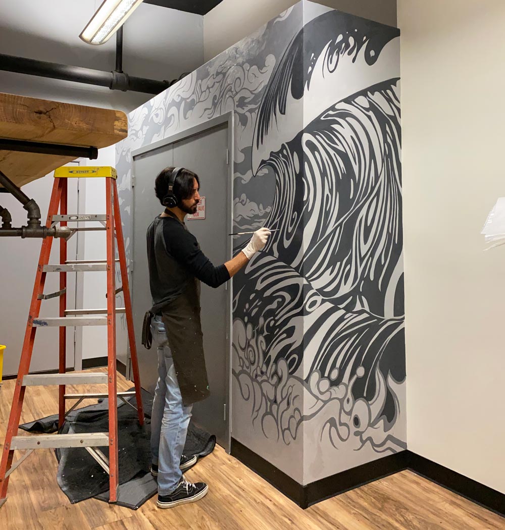 Artist Jay Alders painting an ocean surf theme mural