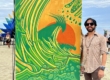 Jay Alders' modern mural at Sea Hear Now 2023, featuring an elongated surfer on a dynamic wave, vibrant in color and emotion